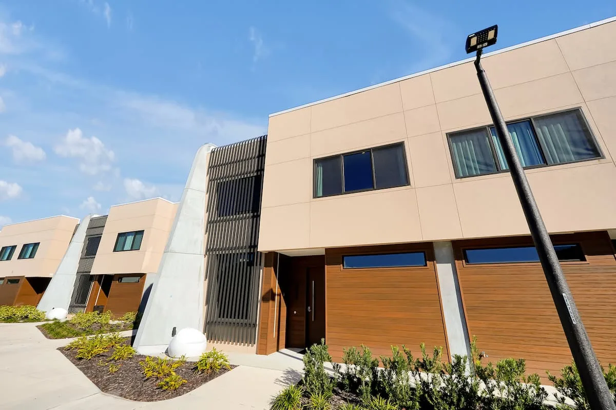 Facade of a completed home at Magic Village by Pininfarina, with its curved concrete pillar and wooden louvres